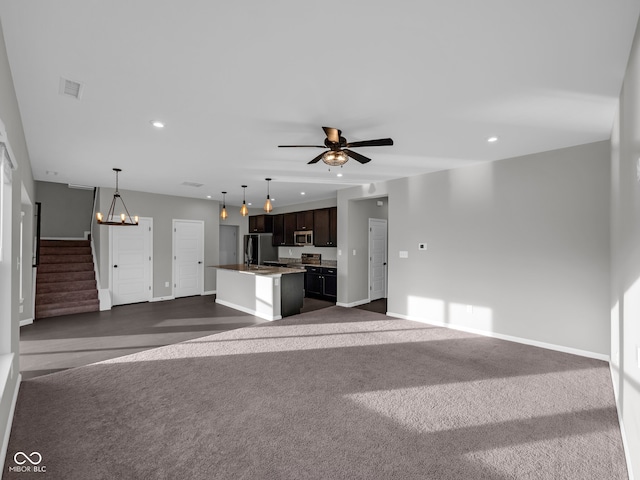 unfurnished living room featuring ceiling fan with notable chandelier and dark colored carpet