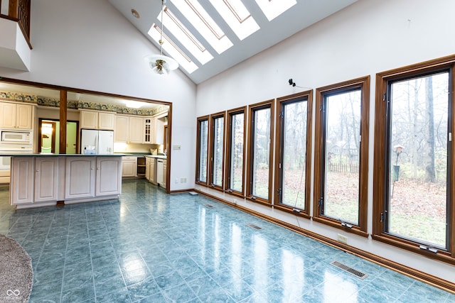 unfurnished living room featuring a skylight and high vaulted ceiling