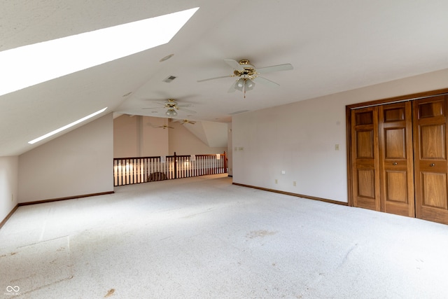 bonus room with ceiling fan, vaulted ceiling with skylight, and carpet floors