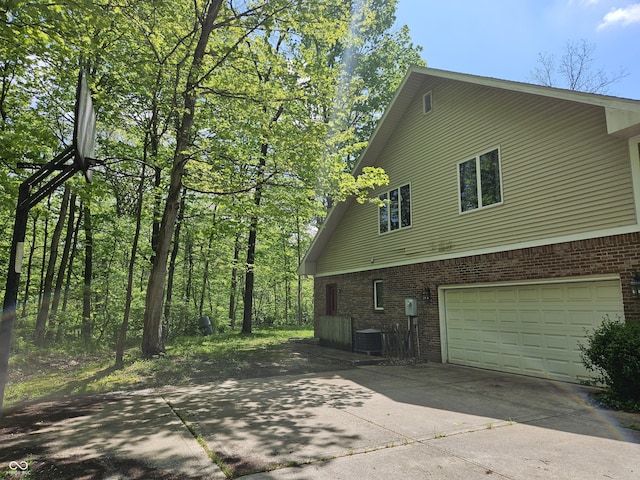 4257 Tattersall Dr, Plainfield, IN 46168 - view of side of home featuring concrete driveway, brick siding, an attached garage, and cooling unit