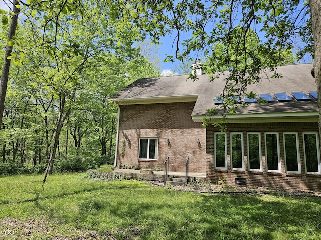 4257 Tattersall Dr, Plainfield, IN 46168 - view of home's exterior featuring brick siding, a lawn, roof mounted solar panels, and a chimney