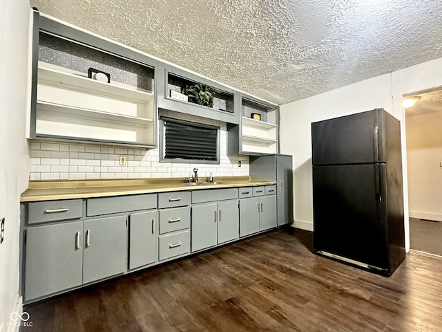 kitchen featuring sink, dark wood-type flooring, wood counters, black fridge, and backsplash