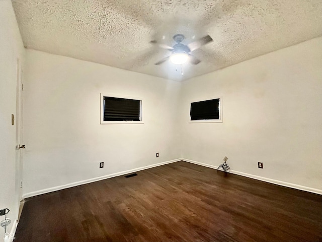 empty room featuring dark hardwood / wood-style floors, ceiling fan, and a textured ceiling