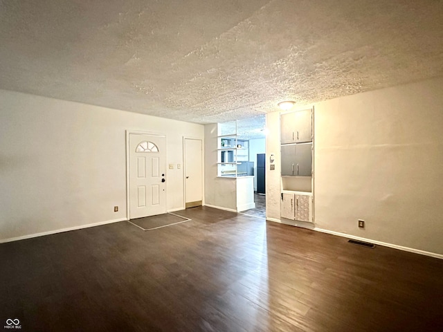 foyer entrance with dark hardwood / wood-style floors and a textured ceiling