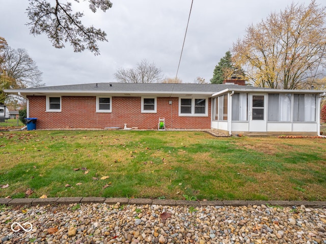 rear view of property featuring a lawn and a sunroom