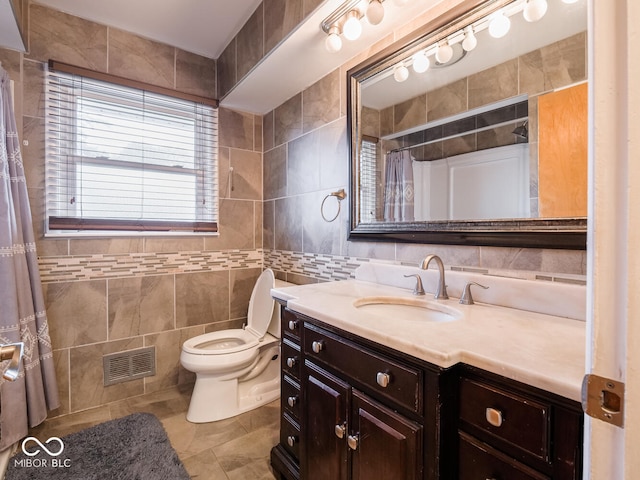 bathroom featuring tile patterned flooring, vanity, tile walls, and toilet