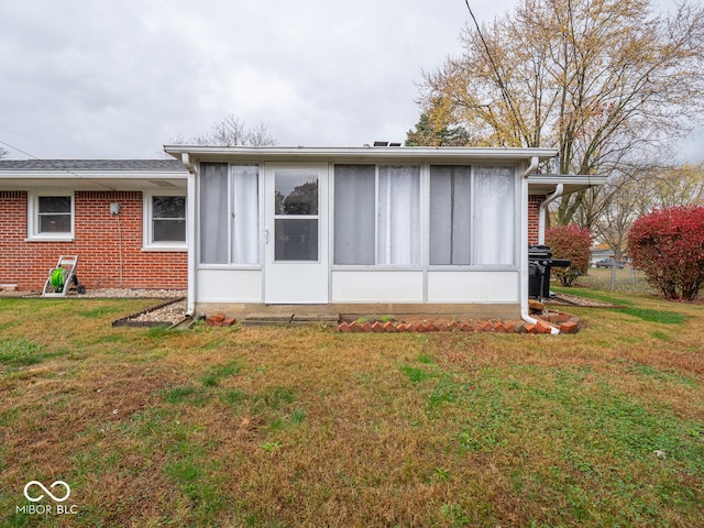 back of property featuring a sunroom and a lawn