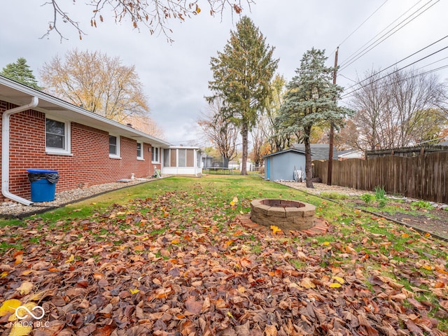 view of yard with a fire pit, a storage shed, and a sunroom