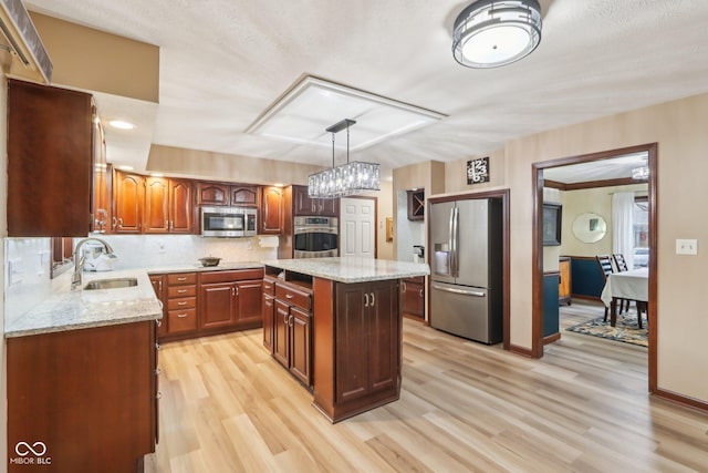 kitchen with sink, hanging light fixtures, light hardwood / wood-style flooring, a kitchen island, and stainless steel appliances