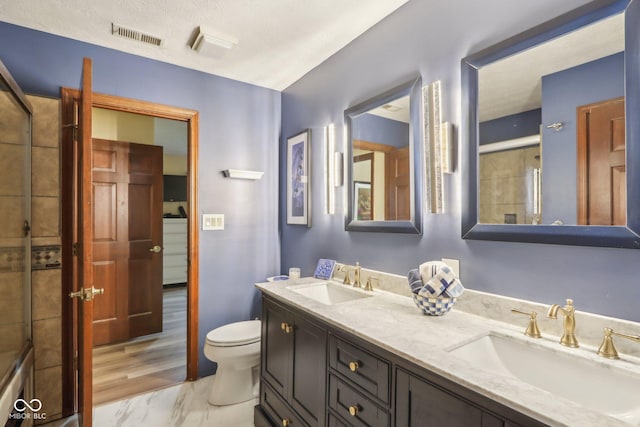 bathroom featuring vanity, a shower with shower door, and toilet