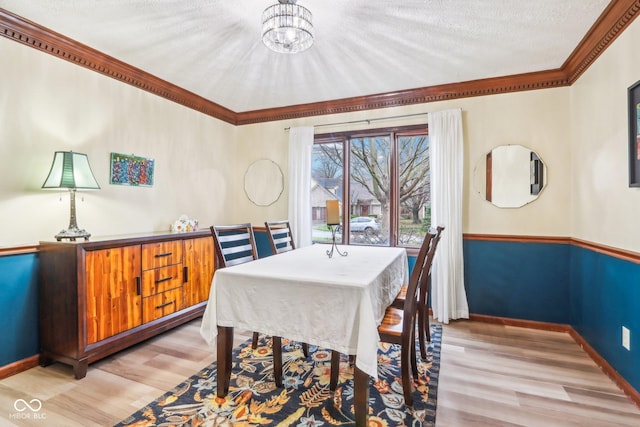 dining space with light hardwood / wood-style flooring, ornamental molding, a textured ceiling, and an inviting chandelier