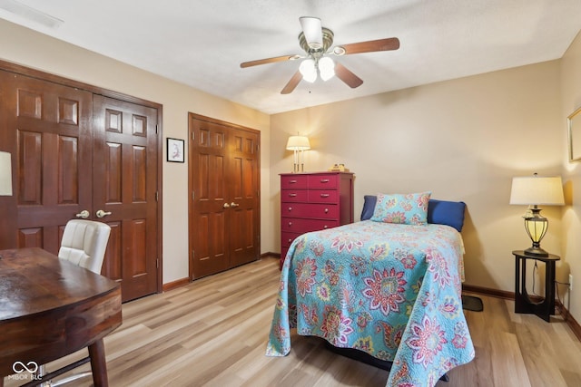 bedroom featuring light wood-type flooring, ceiling fan, and multiple closets