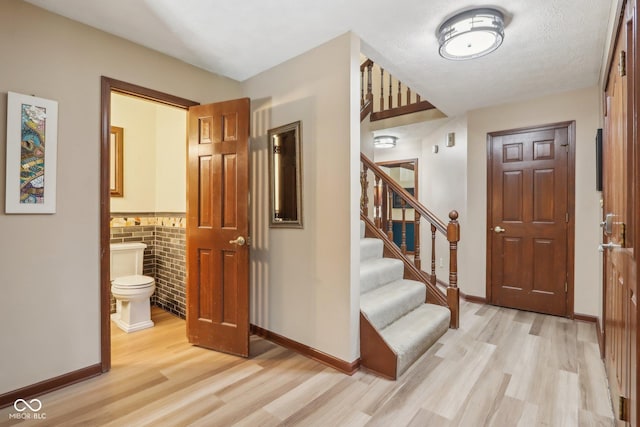 entryway with light hardwood / wood-style floors and brick wall