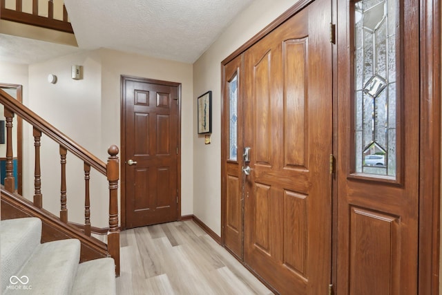 foyer with a textured ceiling and light wood-type flooring