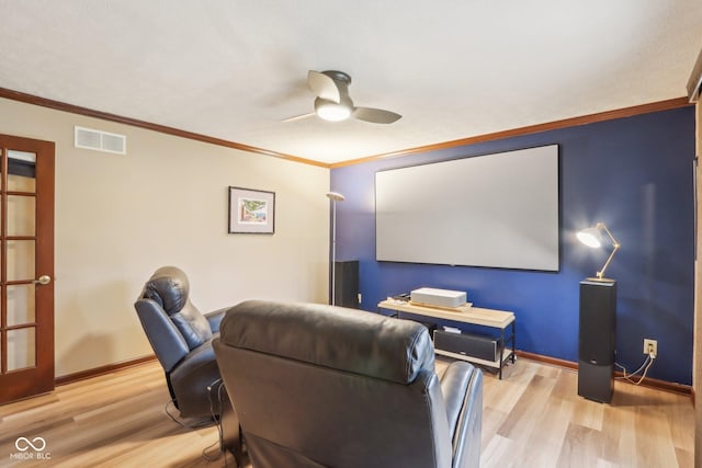 home theater with ceiling fan, light hardwood / wood-style flooring, and ornamental molding