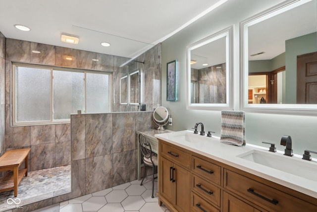 bathroom featuring tile patterned flooring, vanity, tile walls, and tiled shower