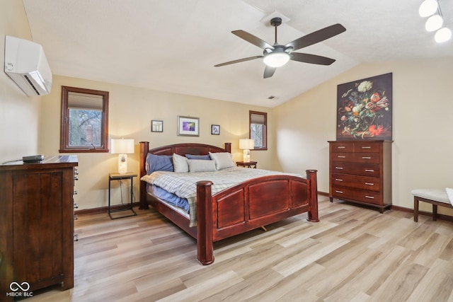 bedroom with ceiling fan, light wood-type flooring, a wall unit AC, and vaulted ceiling