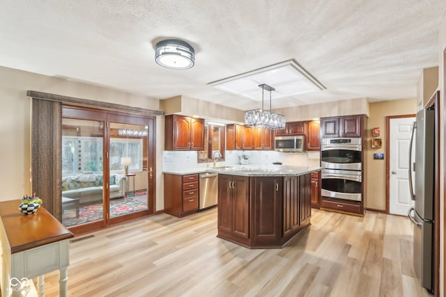 kitchen featuring sink, a center island, backsplash, decorative light fixtures, and appliances with stainless steel finishes