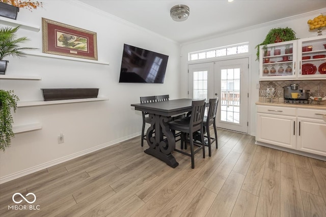 dining room with light hardwood / wood-style floors, crown molding, and french doors