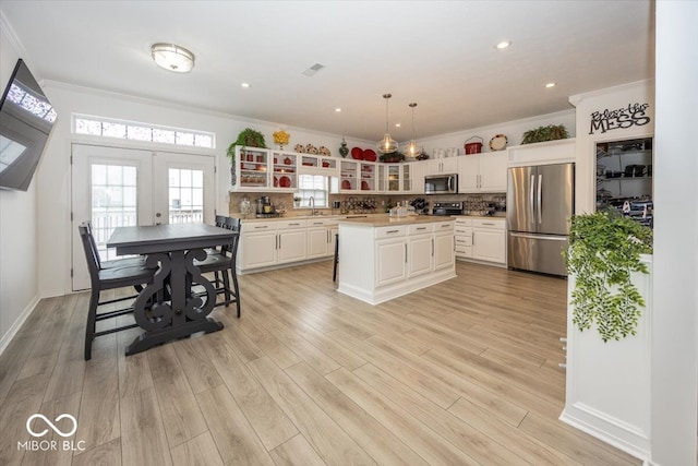 kitchen featuring appliances with stainless steel finishes, a center island, light hardwood / wood-style floors, and pendant lighting