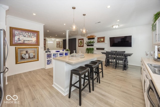 kitchen featuring a kitchen breakfast bar, light hardwood / wood-style flooring, white cabinets, and stainless steel appliances