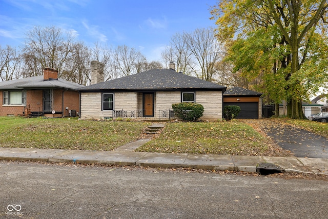 ranch-style home featuring a front lawn, cooling unit, and a garage