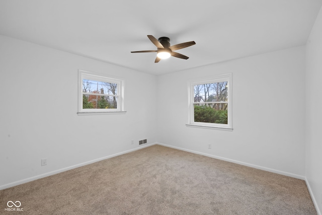 carpeted spare room featuring a wealth of natural light and ceiling fan