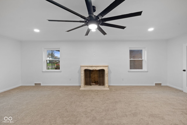 unfurnished living room featuring ceiling fan, a high end fireplace, and light colored carpet