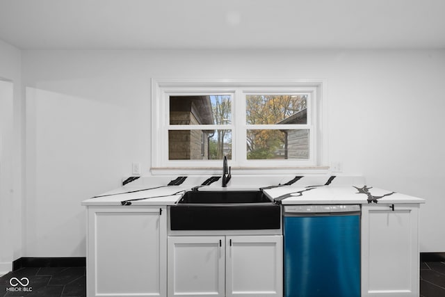 kitchen featuring white cabinetry, dark tile patterned floors, stainless steel dishwasher, and sink