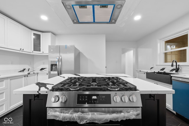 kitchen with white cabinets, sink, dark tile patterned floors, appliances with stainless steel finishes, and a kitchen island