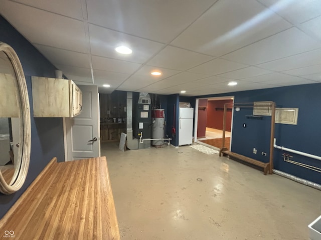 basement featuring heating unit, a drop ceiling, white fridge, and water heater