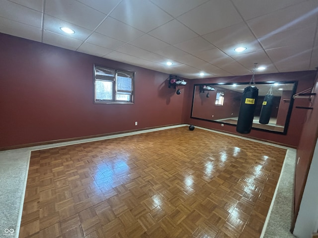 basement with a drop ceiling and parquet flooring