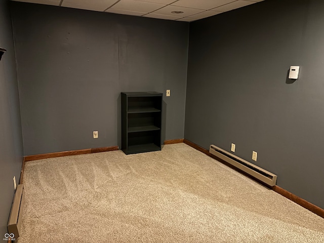 carpeted empty room with a paneled ceiling and a baseboard heating unit