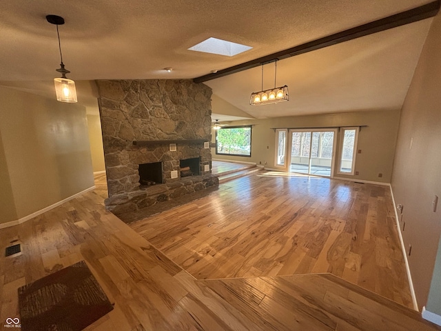 unfurnished living room featuring a fireplace, a textured ceiling, hardwood / wood-style flooring, and lofted ceiling with skylight