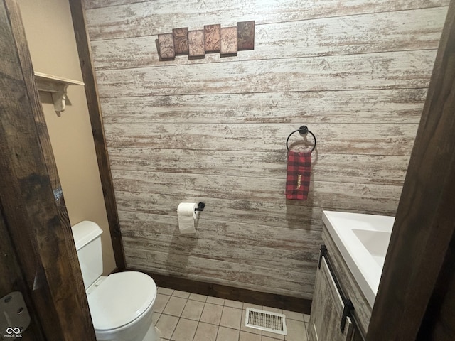 bathroom featuring tile patterned flooring, vanity, wood walls, and toilet