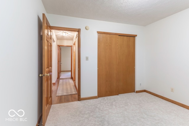 unfurnished bedroom with carpet, a textured ceiling, and a closet