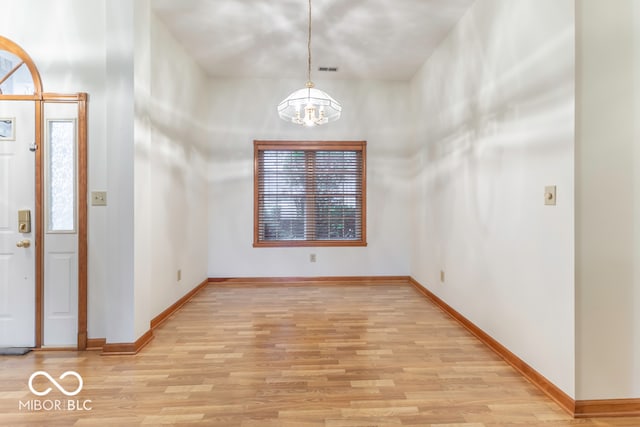 entrance foyer with a chandelier, a towering ceiling, light hardwood / wood-style flooring, and plenty of natural light