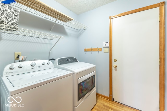 laundry room featuring light hardwood / wood-style flooring, a textured ceiling, and independent washer and dryer