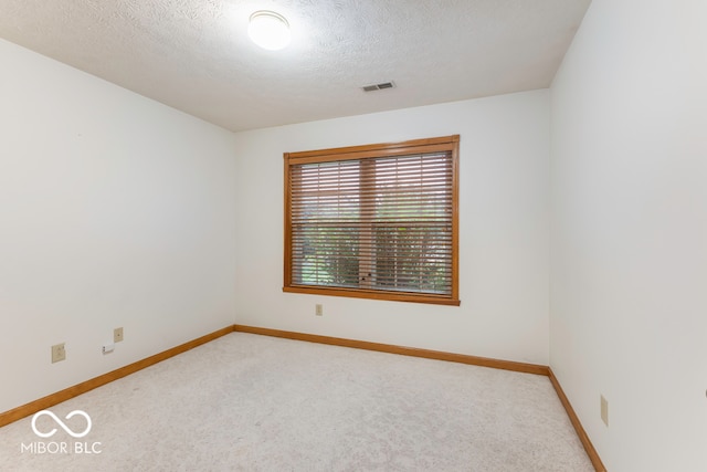 carpeted empty room featuring a textured ceiling