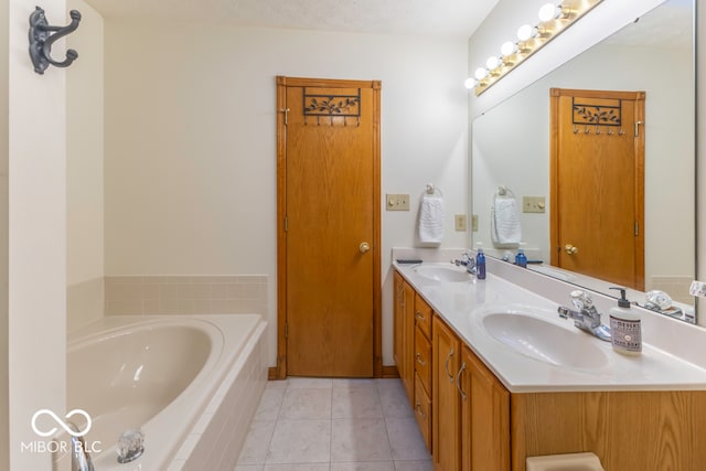 bathroom with tile patterned flooring, vanity, a textured ceiling, and tiled bath