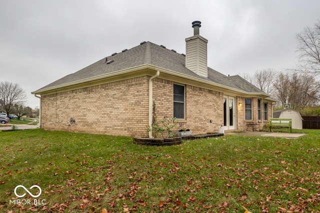 back of house featuring a yard, a patio, and a shed