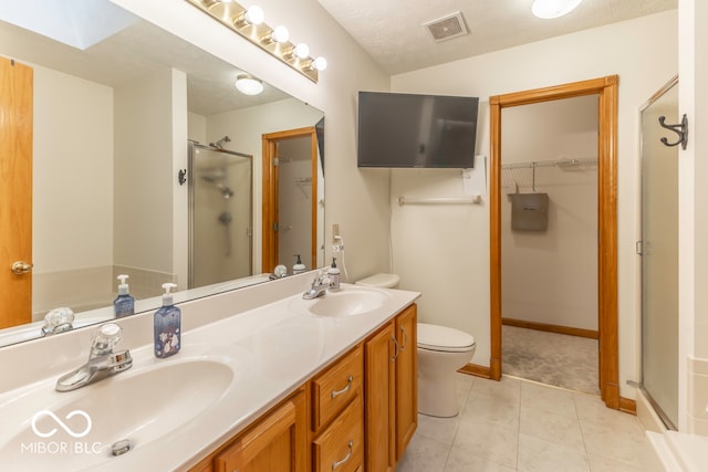 bathroom with tile patterned flooring, vanity, a textured ceiling, and a shower with door