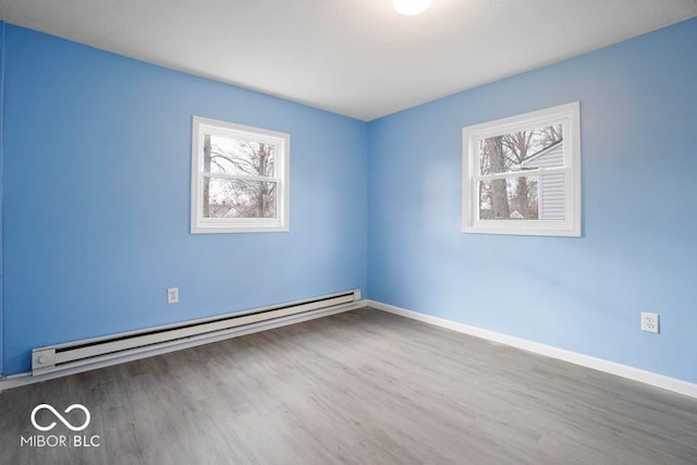 unfurnished room featuring wood-type flooring and a baseboard heating unit