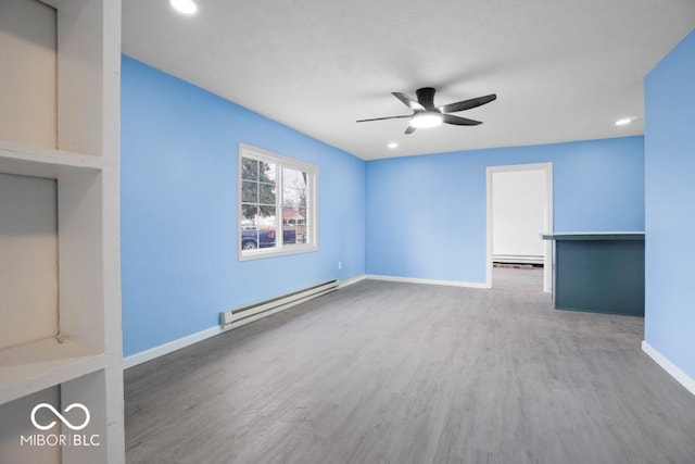 unfurnished living room with ceiling fan, wood-type flooring, and baseboard heating