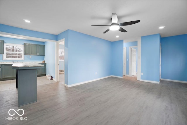 unfurnished living room featuring ceiling fan, light wood-type flooring, and sink