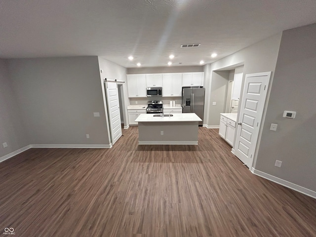 kitchen with dark hardwood / wood-style floors, a barn door, and stainless steel appliances