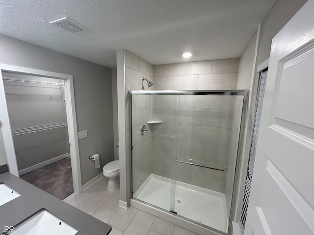 bathroom with tile patterned floors, vanity, toilet, and a shower with door