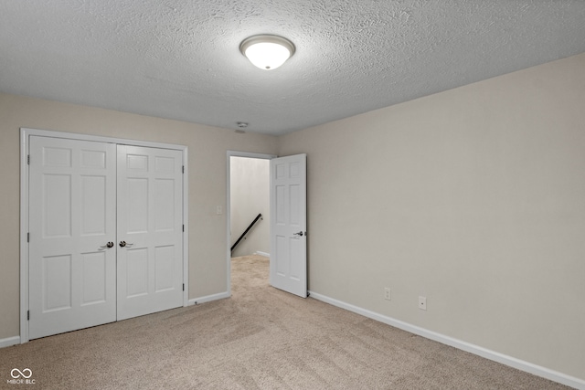 unfurnished bedroom with light colored carpet, a textured ceiling, and a closet