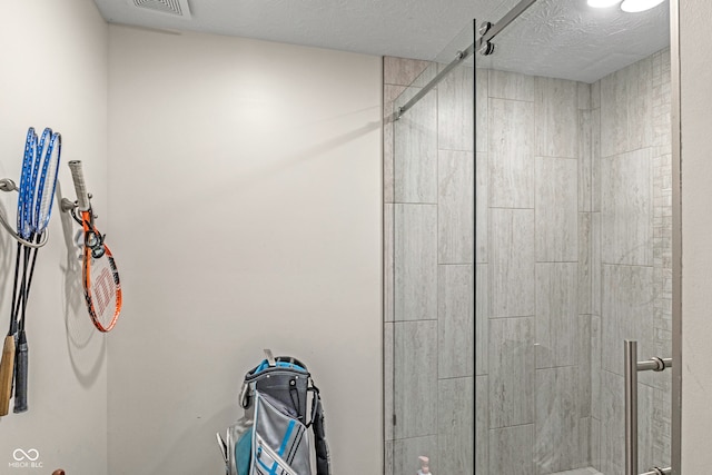 bathroom with a shower with shower door and a textured ceiling