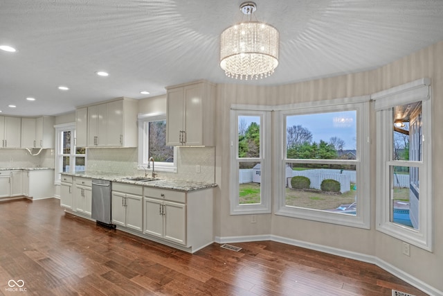 kitchen with dishwasher, dark wood-type flooring, hanging light fixtures, tasteful backsplash, and white cabinets